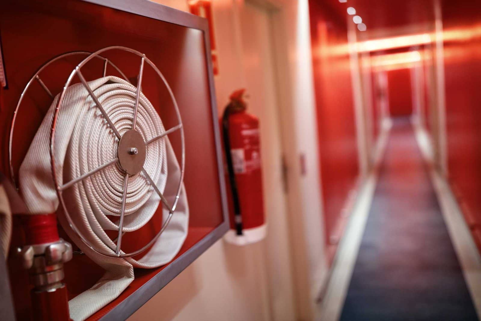 Fire Extinguisher And Hose Reel In Hotel Corridor P7q39e9